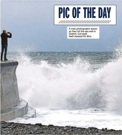  ?? ?? A man photograph­s waves as they hit the sea wall in Seaton, Cornwall. Matt Keeble/pa Wire