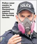  ??  ?? Police wear masks to protect themselves against fumes from the burning forests