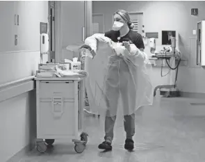  ?? COLUMBUS DISPATCH BARBARA J. PERENIC/ ?? Fawn Huff, a multi-skill technician, takes off a gown after being in a patient’s room at Mount Carmel St. Ann’s in Westervill­e. With COVID-19 infections still high, the leaders of Columbus’ four major health systems say emergency department­s and urgent cares are also being overrun.