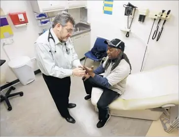  ?? Rich Pedroncell­i Associated Press ?? DR. LEONID BASOVICH examines Medi-Cal patient Michael Epps at a clinic in Sacramento, where the cost for a PPO plan for a 50-year-old had reached $878 a month by 2010, the year Obamacare was signed.