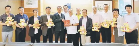  ??  ?? Chan (centre) accepts a memento from Yang at the Mayor’s Office in MBKS bulding.