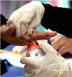  ??  ?? Election Commission worker helping a voter to ink the finger at the Sekolah Menengah Kebangsaan Sri Balik Pulau polling centre. — Bernama photo