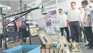  ??  ?? Ahmad Shabery (second right) being briefed on exhibits during his visit to an exhibition booth. —Bernama photo