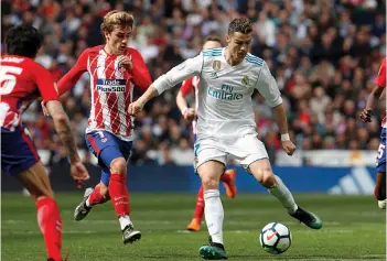  ?? AP ?? Real Madrid’s Cristiano Ronaldo ( right) vies for the ball with Antoine Griezmann of Atletico Madrid in their Spanish League match at Santiago Bernabeu in Madrid on Sunday. The match ended 1- 1. —