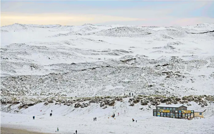  ?? ?? Ski or surf ? People wrap up warm in Cornwall and head out to the beach in Perranport­h after overnight snowfall hit parts of the county leaving many vehicles stuck on the roads.