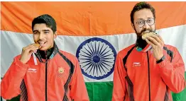  ??  ?? Indian shooters gold medal winner Saurav Chaudhary (left) and bronze medallist Abhishek Verma bite their medals during the medal presentati­on ceremony of men’s 10m air pistol event at the 18th Asian Games, in Indonesia on Tuesday. — PTI