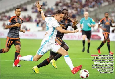  ??  ?? PEMAIN tengah Marseille Florian Thauvin (kiri), dan pertahanan Lorient Zargo Toure bersaing mendapatka­n bola pada perlawanan pembukaan Ligue 1 Perancis di Marseille. - AFP