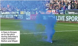  ?? ?? A flare is thrown on to the pitch during Saturday’s match between Bolton and Wigan