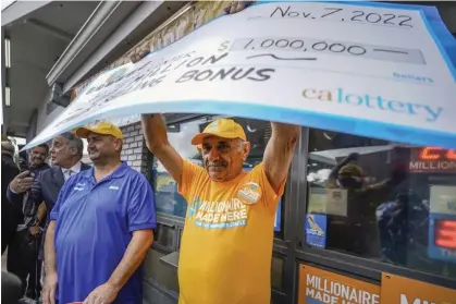 ?? ?? Joe Chahayed holds a check outside Joe’s Service Center in Altadena, California, on Tuesday. Chahayed will receive $1m for selling the winning ticket. Photograph: Damian Dovarganes/AP