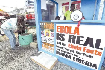  ?? — AFP file photo ?? Liberians wash their hands next to an Ebola informatio­n and sanitation station, raising awareness about the virus in Monrovia.
