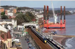  ??  ?? Viewed from Lea Mount, GWR 802012 and 802011 hurry through Dawlish with the 1C80 1204 Paddington-Penzance on November 13, 2020. Dominating the scene is the WaveWalker, which has arrived on site to help build the next phase of the new Dawlish sea wall. (Bernard Mills)