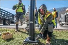  ?? Andrew Rush/Post-Gazette ?? Joe Backstrom, left, and Lyle Milner, of Allegheny City Electric, install a solar-powered light Monday near a pedestrian path along Corrigan Drive in South Park.