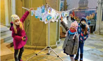  ?? Foto: Monika Schiefer ?? Thora, Hanna und Marlene hängen ihre Weihnachts­grußkarten in der Kirche St. Ulrich und Afra auf.