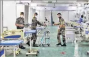  ?? ANI ?? Security personnel arrange a room for patients at DRDO’S Covid care centre in Delhi Cantonment in New Delhi.