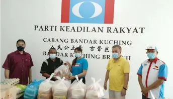  ??  ?? Ng (centre) presents the food items to the family’s representa­tive at PKR Bandar Kuching office.
