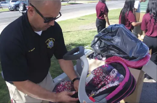  ?? PHOTO TOM BODUS ?? California Highway Patrol officer Javier Amezcua inspects a car seat at Saturday’s car seat clinic at Pioneers Memorial Hospital.