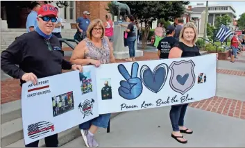  ?? Olivia Morley ?? William Wagner (from left), Cindy Wagner and Kyrie Wagner hold up a homemade sign with pictures of their family members in law enforcemen­t and public safety at the Back the Blue Rally late Monday afternoon at Rome City Hall.