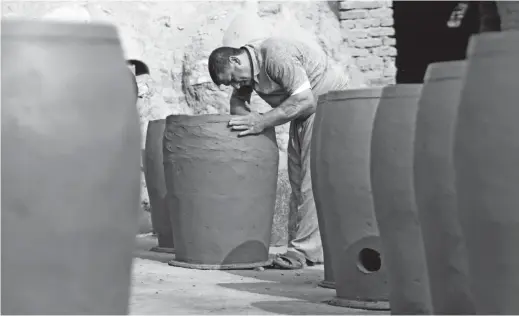  ??  ?? Iraqis making clay pots in Najaf. Pottery has deep roots in Iraq, where ancient civilizati­ons turned to clay to build their homes, shape their cooking utensils, and even make their ovens. — AFP