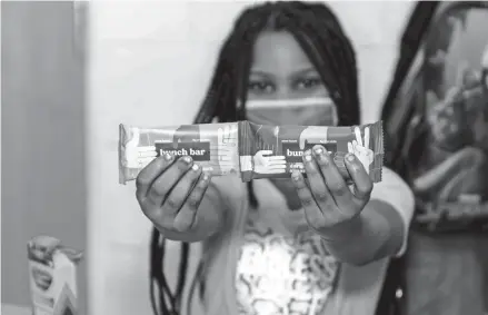  ?? COURTESY OF BOYS & GIRLS CLUBS OF GREATER MILWAUKEE ?? A girl at a Boys & Girls Club in Milwaukee holds Bunch Bars. Every box of Bunch Bars sold brings a donation of two bars to organizati­ons such as the clubs.