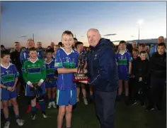  ??  ?? AGB Captain Aaron O’Brien is presented the U-13 ‘B’ football championsh­ip trophy by Coiste na ng chairman Pat Dunne in Ballinakil­l.