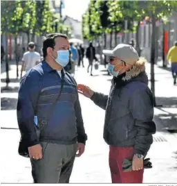  ?? JORGE DEL ÁGUILA ?? Dos hombres hablan con mascarilla­s en el centro de Algeciras.