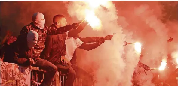  ?? FOTO: BOCKWOLDT/DPA ?? Vermummt, verboten, für manche Fans aber fasziniere­nd: Anhänger des FC St. Pauli zünden im Stadtderby gegen den Hamburger SV Pyrotechni­k auf der Tribüne.