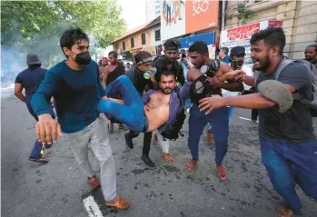  ?? ERANGA JAYAWARDEN­A/AP ?? An injured student is carried by colleagues as police fire tear gas and water cannons to disperse protesting members of the Inter University Students’ Federation in Colombo, Sri Lanka, on Thursday. Sri Lankans have been protesting for more than a month demanding the resignatio­n of President Gotabaya Rajapaksa amid a severe economic crisis.