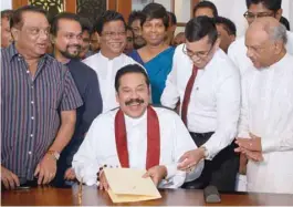  ??  ?? Sri Lanka’s former president Mahinda Rajapakse reacts after signing a document backing down from his controvers­ial appointmen­t as prime minister in Colombo. — AFP