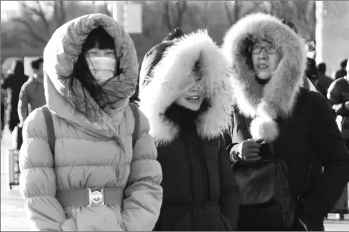  ?? DU JIA / FOR CHINA DAILY ?? Tourists wear thick down jackets walking on Chang’an Street in Beijing.