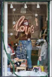  ?? (AP/Tony Dejak) ?? Samantha Probst decorates her store window at Little Babet, a children’s boutique shop, Tuesday in Chagrin Falls, Ohio.