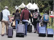  ?? CHARLES KRUPA/THE ASSOCIATED PRESS ?? A Haitian family approaches a tent managed by the RCMP in St-Bernardde-Lacolle. A growing backlog at the Immigratio­n and Refugee Board means claimants face long delays, says Louis Dumas, of Immigratio­n, Refugees and Citizenshi­p Canada.