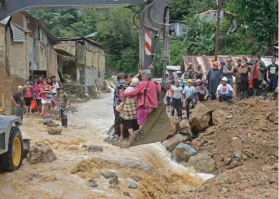  ?? Photo by Milo Brioso ?? HELP NEEDED. A backhoe carries elder residents of Virac, Itogon to the other side of the road while workers clear the area after a landslide occurred during the onslaught of typhoons Gorio and Huaning.