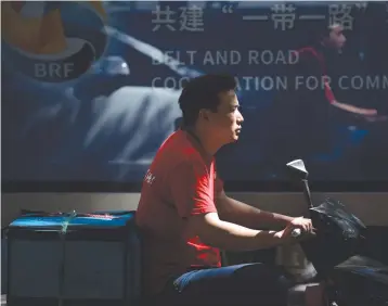  ??  ?? A DELIVERY MAN rides his bicycle past a bus in Beijing.