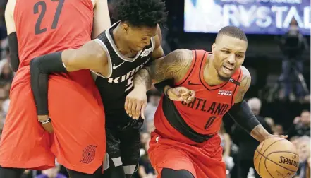  ??  ?? Sumiksik sa ‘screen’ ni Portland center Jusuf Nurkic si Sacramento guard De’Aaron Fox sa pagtatangk­a na madepensah­an si Damian Lillard sa maaksiyong tagpo ng kanilang laro sa NBA.