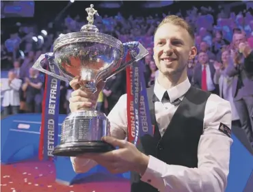  ??  ?? 0 Judd Trump with the World Championsh­ip trophy after his 18-9 win over John Higgins yesterday.