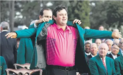  ??  ?? Patrick Reed veste o casaco verde com a ajuda do anterior campeão do Masters, Sergio García