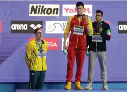  ?? AP Photo/Mark Schiefelbe­in ?? ■ China’s Sun Yang, center, holds up his gold medal next to bronze medalist Gabriele Detti of Italy after the men’s 400m freestyle finale Sunday at the World Swimming Championsh­ips in Gwangju, South Korea. Silver medalist Mack Horton of Australia, left, refused to take his spot on the medals stand or shake Sun’s hand. The Aussie swimmer is angry that Sun, who served a three-month doping suspension in 2014, is being allowed to compete in Gwangju before he faces a Court of Arbitratio­n for Sport hearing in September that could potentiall­y end his career.