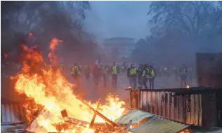  ?? - AFP file photo ?? PROTEST: Demonstrat­ors gather near a fire burning during a protest of Yellow vests (Gilets jaunes) against rising oil prices and living costs, near the Arc de Triomphe in Paris.