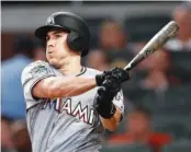  ??  ?? The Miami Marlins’ J.T. Realmuto follows through on a two-run base hit in the fourth inning. He also homered.