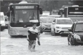  ?? LYU WENZHENG / FOR CHINA DAILY ?? A man walks through a flooded street in Dalian, Liaoning province, on Monday. Typhoon Rumbia brought torrential rains and caused severe flooding in the city.