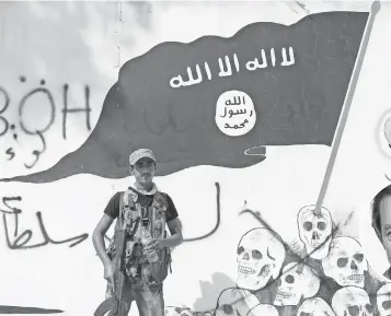  ?? DEFNE KARADENIZ, GETTY IMAGES ?? A member of the Turkish- backed Free Syrian Army in the border town of Jarablus, Syria, stands guard in front of a ISIL flag in August. The town had been held by the Islamic State.