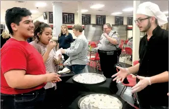  ?? SALLY CARROLL/MCDONALD COUNTY PRESS ?? Eugenio Mendoza Jr. (left) and Yailin Delgado try some birthday cake bon-bons as Anton Mart describes the variety of delectable­s available at the 27th Annual Internatio­nal Food Fest at the McDonald County High School.
