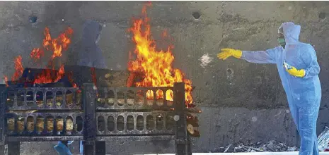  ?? AP ?? A municipal worker performs last rites during the cremation of a COVID-19 fatality in Vasai, on the outskirts of Mumbai, India on Thursday.