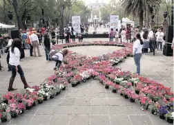  ?? PICTURE: EPA ?? GLOBAL STRUGGLE: Women arrange flowers to form the shape of a ribbon during the World Cancer Day celebratio­ns in Mexico City.