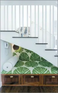  ?? AMY BARTLAM — AMY SKLAR DESIGN VIA AP ?? This photo provided by Amy Sklar Design shows a nook under some home stairs that Sklar designed. Sklar tucked a smartlydec­orated nook under these stairs – the perfect little hideaway for reading or a quiet phone chat. The fabric, by Raoul Textiles, is called Elephant Leaf. Sklar had it backed to use as wallpaper as well. It is also used for the living room drapery – a decorating trick we’re seeing more and more of as a way to tie spaces together.