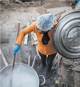  ?? RODRIGO ABD/AP ?? Efraina Rivera stirs oatmeal in a “community pot” in Lima, Peru. Food from these pots is helpful as millions deal with the coronaviru­s while being unable to feed their families.