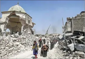  ?? AHMAD AL-RUBAYE/AFP ?? Iraqis walk past the destroyed Al-Nuri Mosque as they flee from the Old City of Mosul on July 5.
