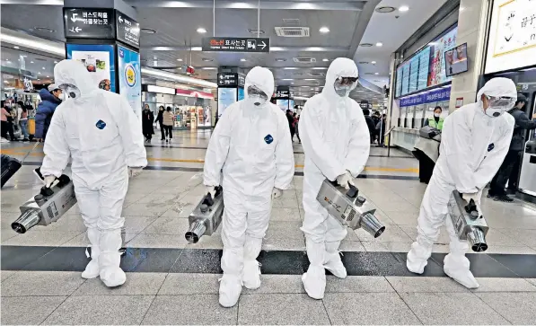  ??  ?? Health officials wearing hazmat suits disinfect a main bus terminal in Wuhan city with sprays in an effort to contain the coronaviru­s outbreak