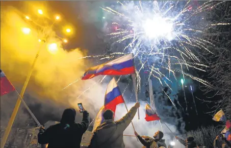  ?? AGENCIES ?? People wave Russian national flags celebratin­g the decision and (bottom) a tank drives along a street in Donetsk.