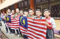  ??  ?? MURID Tahun Enam bersemanga­t mengibarka­n Jalur Gemilang.